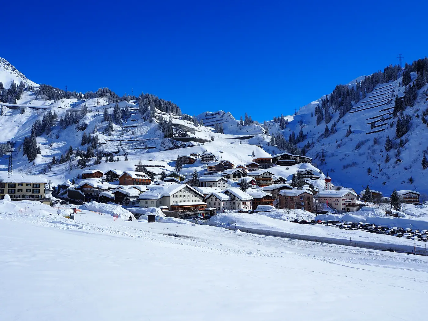 Stuben am Arlberg im Winter: verschneite Häuser am Hang unter tiefblauem Himmel